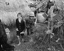 A Marine from 1st Battalion, 3rd Marines, moves a suspected Viet Cong during a search and clear operation held by the battalion 15 miles (24 km) west of Da Nang Air Base, 1965.