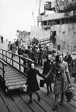 A Dutch school teacher leads a group of refugee children just disembarked from a ship at Port of Tilbury in Essex, England, United Kingdom during 1945.