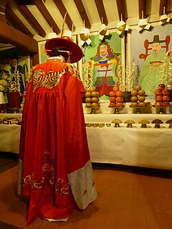 A diorama showing a mudang with lowered head in a shrine