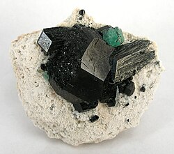 A single stark green fluorite isolated on top of schorl crystals