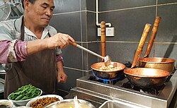 Mixian (米线) rice noodles being cooked in copper pots (铜锅) on gas elements at a noodle restaurant in Kunming.