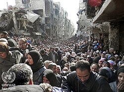Residents of Yarmouk Camp line up to receive UNRWA aid during the Syrian civil war, January 2014