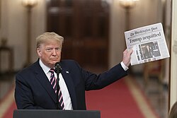 Donald Trump holds up a copy of The Washington Post during remarks on February 6, 2020, in the East Room of the White House.