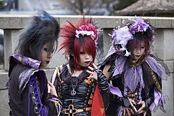 The Jingūbashi, which passes over the Yamanote Line south of Harajuku Station in Tokyo, near the gate of Meiji Shrine, is a well-known gathering place for cosplayers. Pictured is a group of people dressed as visual kei-style musicians in 2006.