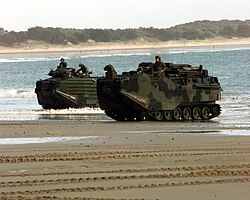 Marine Amphibious Assault Vehicles emerge from the surf onto the sand of Freshwater Beach, Australia