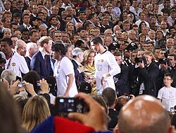 A man in a white shirt receives a medal from a man in a suit.
