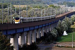High-speed line on a viaduct to avoid ramp and road-crossing, with a British Rail Class 373 from Eurostar in old livery crossing it.