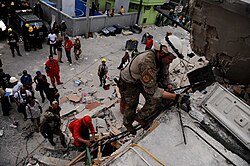 A USAF pararescueman searching through demolished buildings in Port-au-Prince for survivors