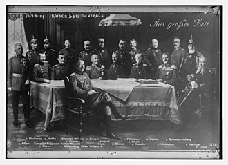 Emperor Wilhelm II in an undated photo. Bethmann Hollweg is second from the right, standing. The German words above him mean "From a Great Time".