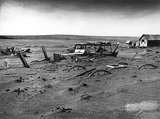 A South Dakota farm during the Dust Bowl, 1936. Normal tillage practices turn South Dakota's fragile soil into a fine, loose powder that blows away, and sometimes covered vehicles, equipment, and buildings with dust during the Dust Bowl.[42]