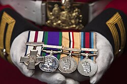The CGC (left) as worn on a dress uniform with campaign medals. The medals shown are those awarded to Lance Corporal of Horse Andrew Radford, CGC.