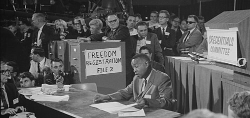 Aaron Henry reading from a document while seated before the Credentials Committee