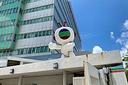 Modern, green-and-white building with dish antennas on top