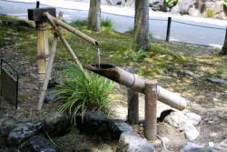 A shishi-odoshi powered by falling water breaks the quietness of a Japanese garden with the sound of a bamboo rocker arm hitting a rock.