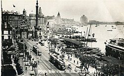 A black and white postcard showing the Shanghai Bund, with streetcars and European-style buildings