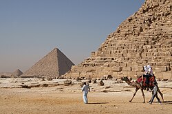 Tourists riding a camel in front of Pyramid of Khafre. The Giza Necropolis is one of Egypt's main tourist attractions.