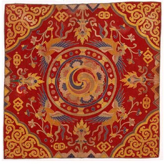 A thrikhep (throne cover) from the 19th century. Throne covers were placed atop the temple cushions used by high lamas. The central circular swirling symbol is the gankyil in its mode as the "Four Joys".