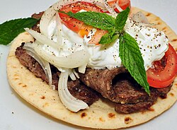 A gyro sandwich garnished with mint leaves