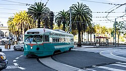 An F Market streetcar turns at the foot of Market Street, in front of the Ferry Building