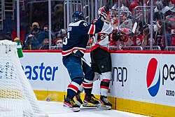 A player checks an opposing skater into the board that surrounds the ice.