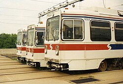 Three abreast white LRVs with a red stripe around the vehicle ends.