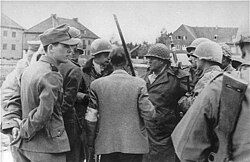 SS men confer with General Henning Linden (man with helmet, looking to his right) during the camp's liberation (29 April 1945)