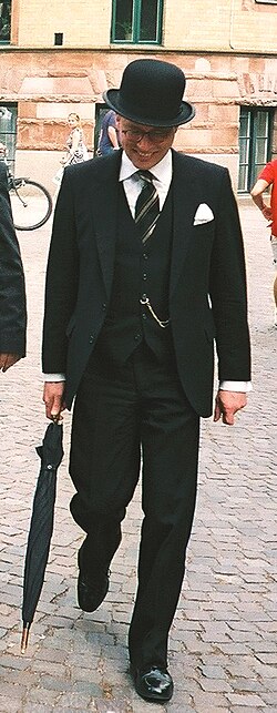 A man dressed in a three-piece suit and bowler hat