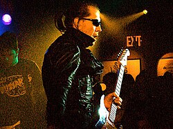 Link Wray, pictured in 1993, who helped pioneer the use of guitar power chords and distortion as early as 1958 with the instrumental "Rumble", has been cited as an early influence on garage rock.