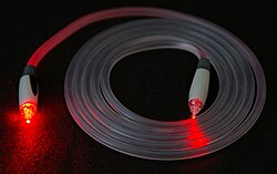 A TOSLINK fiber optic audio cable with red light shining in one end and out the other