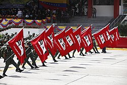 Members of the Venezuelan armed forces carrying Chávez eyes flags saying, "Chávez lives, the fight continues"