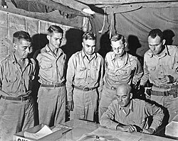 Staff meeting of the U.S. 112th Regimental Combat Team in Arawe with General Julian Cunningham (seated), standing left to right: unidentified, Lieutenant Colonel C. E. Grant, Major D. M. McMains, Colonel A. M. Miller and Lieutenant Colonel P. L. Hooper