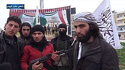 Syrian rebels deface a Ba'athist mural at the Mihrab roundabout in Idlib, after the city's capture by rebel forces in 2015