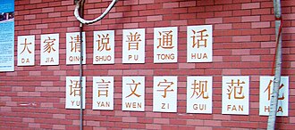 A slogan written on a school wall featuring pinyin annotations without tonal marks or word grouping