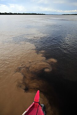 The confluence of the Madeira River (brown) and Aripuanã River (dark) near the town of Novo Aripuanã.