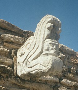 Ballcourt marker from the Postclassic site of Mixco Viejo in Guatemala. This sculpture depicts Kukulkan, jaws agape, with the head of a human warrior emerging from his maw.[160]