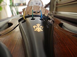 Closeup of a violin tailpiece, with a fleur-de-lis