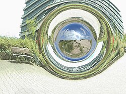 Image of a simulated traversable wormhole that connects the square in front of the physical institutes of University of Tübingen with the sand dunes near Boulogne-sur-Mer in the north of France. The image is calculated with 4D raytracing in a Morris–Thorne wormhole metric, but the gravitational effects on the wavelength of light have not been simulated.[note 1]