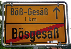 The "Rechtschreib­grenze" ("Correct Spelling Boundary"): traffic sign leaving "Preußisch-Bösgesäß" and stating that Hessisch-Bös-Gesäß is 1 km away[204]