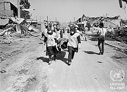 Medical staff carry a dead body in Shatila camp, Beirut, Lebanon, on 20 September 1982.