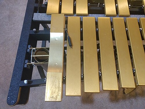 The underside of the low F3 bar is exposed, showing the tuning marks, a disc, and the pins and cord used to hold the bar.