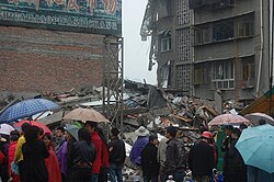 Rain was among the many problems affecting the area in the aftermath of the earthquake. Here, a group of onlookers examine a collapsed building in the rain.