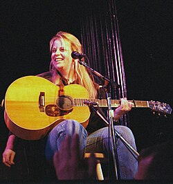 Singer Mary Chapin Carpenter, seated while holding a guitar