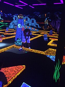 Golfer golfing at Monster Mini Golf, an indoor glow in the dark mini golf course