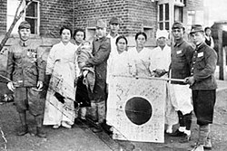 A young Korean conscript in the 1940s posing with his family while holding a Japanese flag.