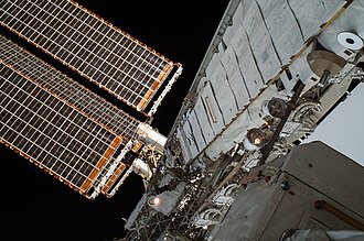 EVA view of the ISS solar arrays and steel truss structure. The white cladding are Kevlar panels to protect from micro-meteoroids