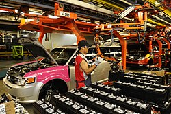 A worker at the Oakville Assembly installs a battery in an automobile. The automotive industry is a contributor to the economy of Ontario.