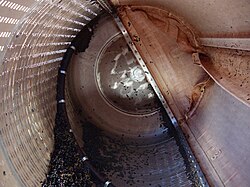 Inside of a membrane press with the deflated membrane mounted to the right side of the tank. Also pictured is left-over pomace (grape skins and seeds) from pressing.