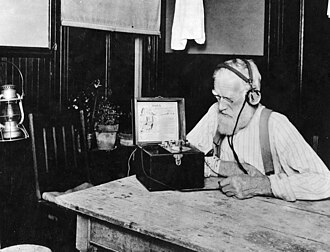 Farmer listening to U.S. government weather and crop reports using a crystal radio in 1923. Public service government time, weather, and farm broadcasts were the first radio "broadcasts".