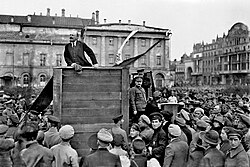 Vladimir Lenin speaks in Moscow, 1920, with Leon Trotsky leaning against the podium.