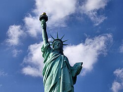 Liberty Enlightening the World, known as the Statue of Liberty, on Liberty Island in New York Harbor, a globally recognized symbol of both the United States and its ideals of freedom, democracy, and opportunity.[121]